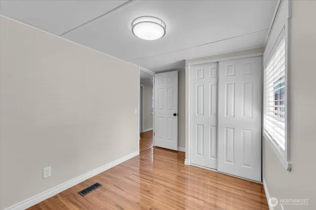 a view of an empty room with wooden floor and a window