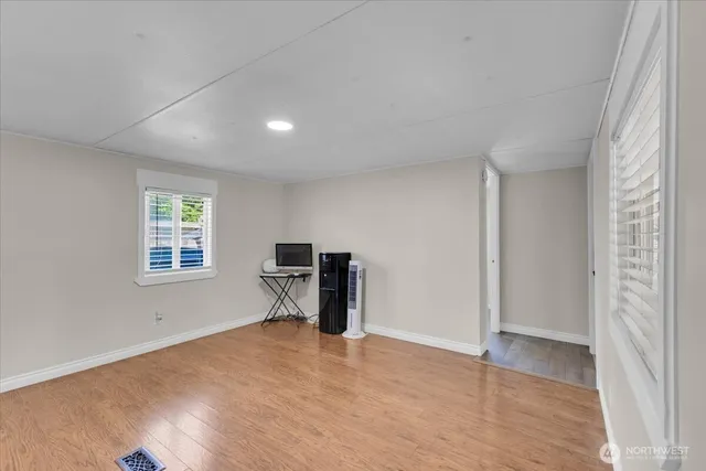 a view of an empty room with a window and a kitchen