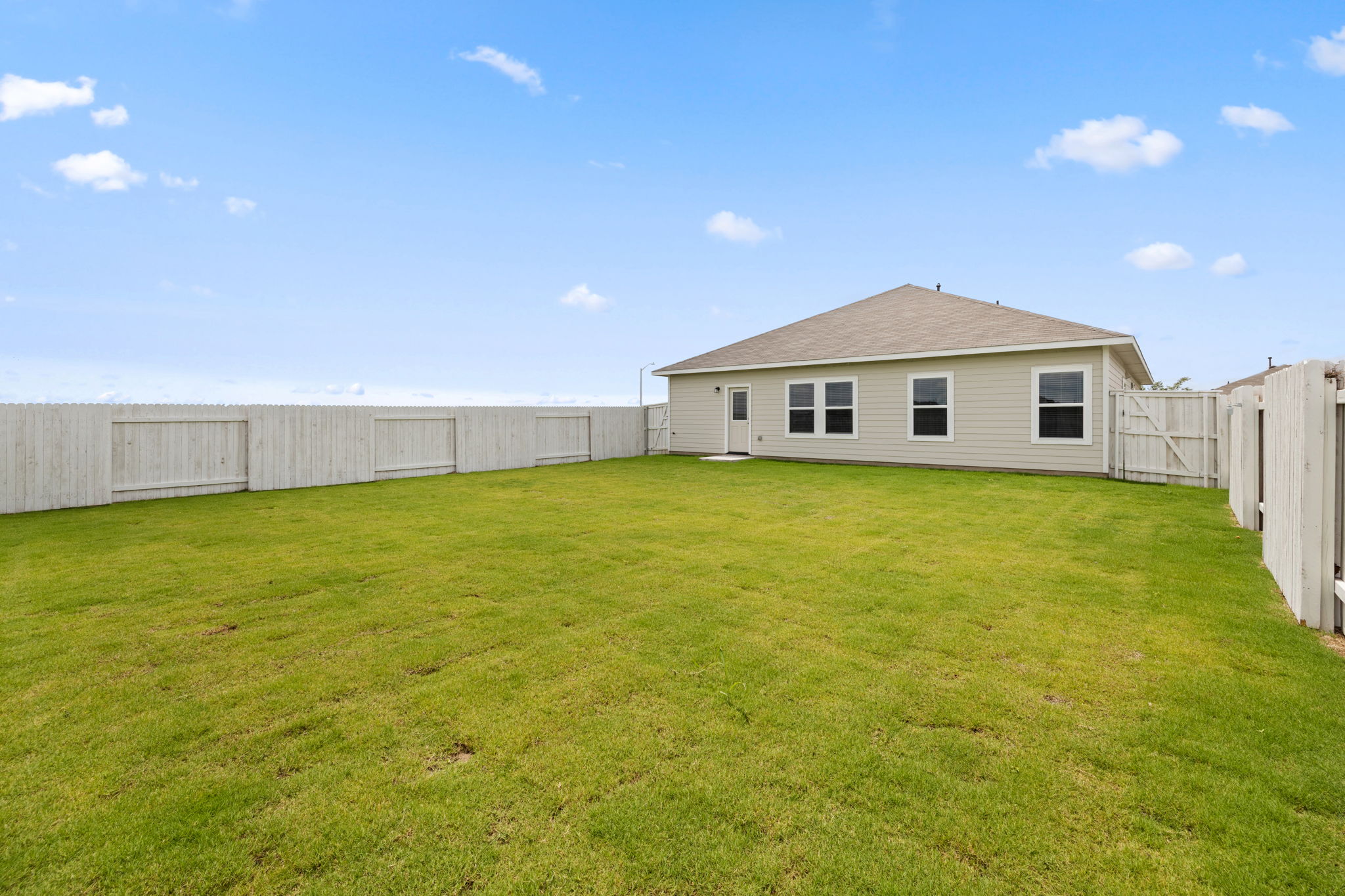 2460 Winding Creek Road Kyle, TX 78640 - Photo 19 of 20 A spacious backyard with vibrant green grass offers ample room for outdoor activities.