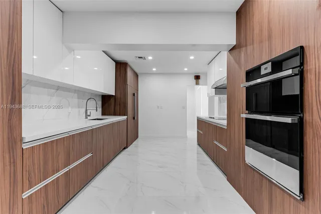 a kitchen with stainless steel appliances kitchen island granite countertop a refrigerator and a sink