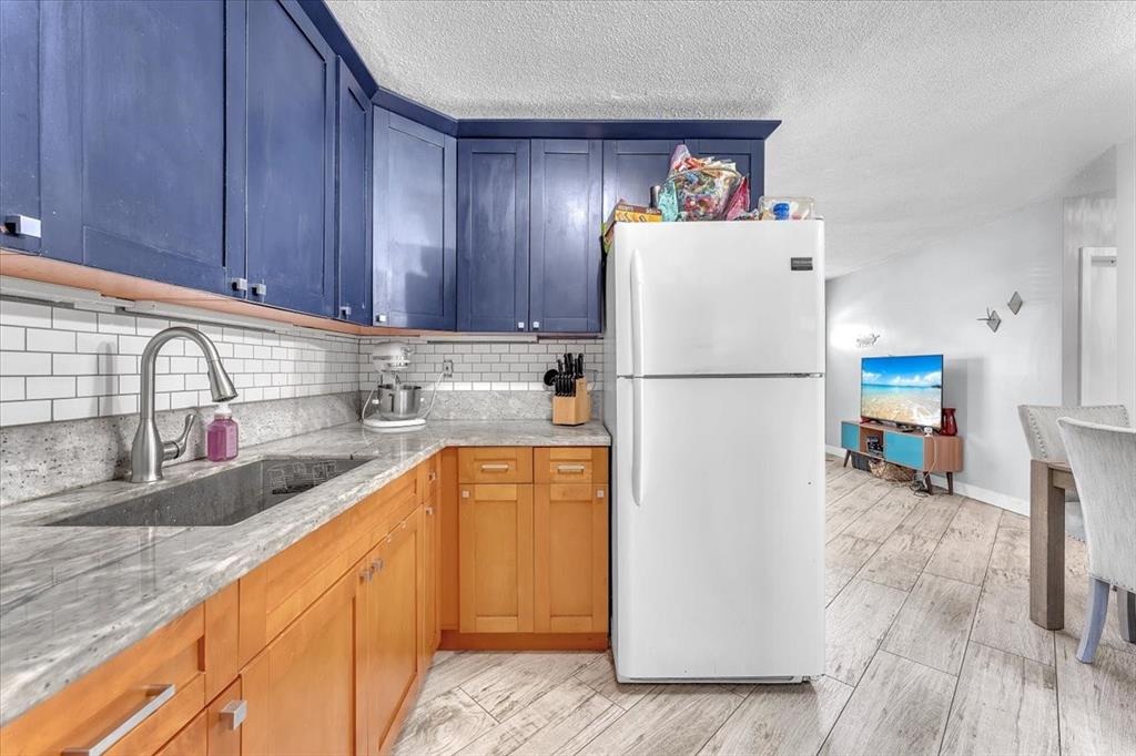 6621 Southwest 19th Street Pompano Beach, FL 33068 - Photo 7 of 16 a kitchen with stainless steel appliances granite countertop a refrigerator sink and wooden cabinets