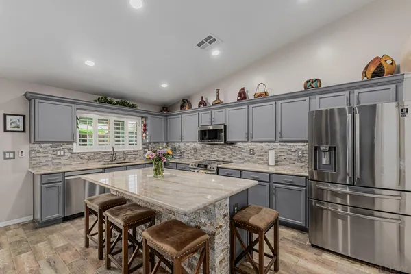a kitchen with stainless steel appliances granite countertop a sink and a refrigerator