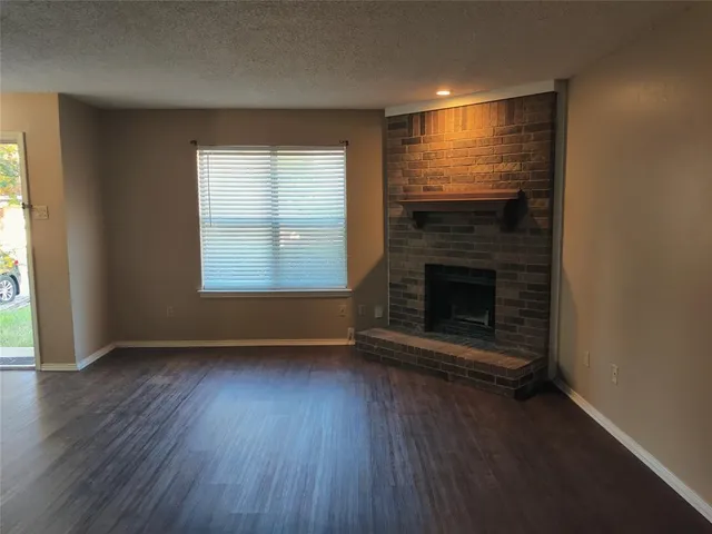 an empty room with wooden floor fireplace and windows
