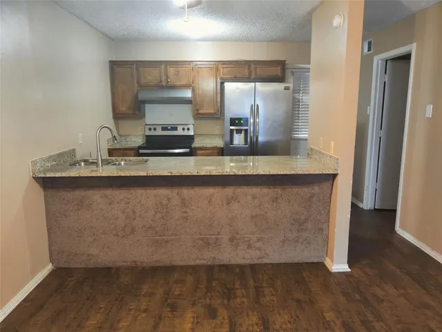 a view of a counter top space with granite countertop a sink and a mirror