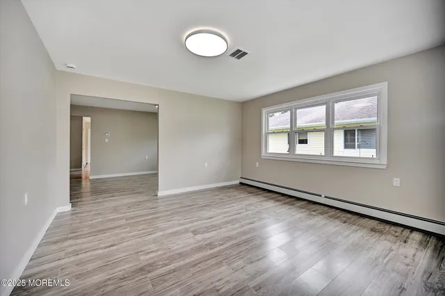 a view of an empty room with wooden floor and a window