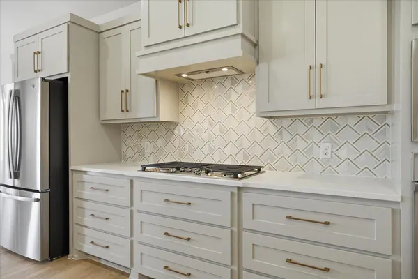 a kitchen with white cabinets and a stove with a refrigerator