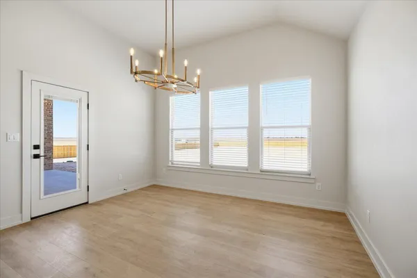 an empty room with chandelier fan and windows