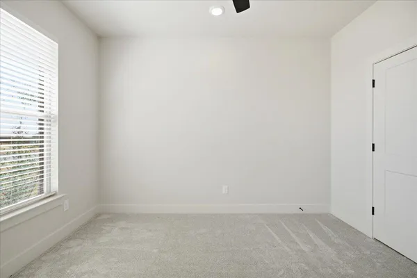 an empty room with windows and fan