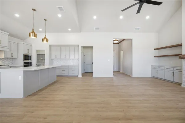 a view of large kitchen with stainless steel appliances granite countertop a stove a sink a refrigerator and white cabinets