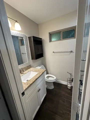 a bathroom with a granite countertop toilet sink and mirror