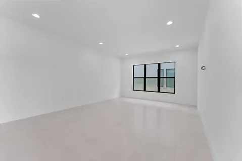 a large white kitchen with kitchen island a sink a stove a refrigerator a white cabinets and couches