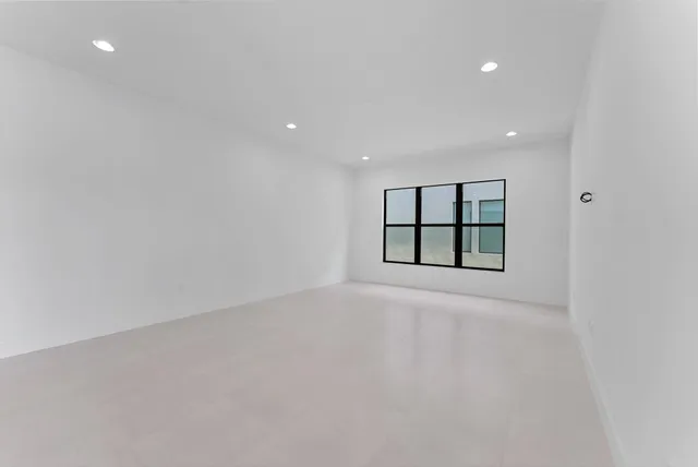 a large white kitchen with kitchen island a sink a stove a refrigerator a white cabinets and couches