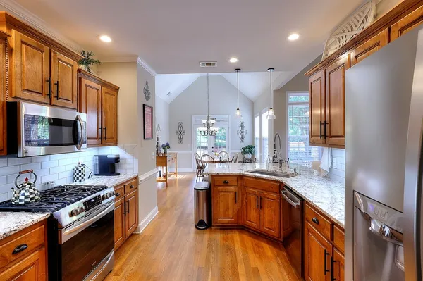 a kitchen with stainless steel appliances granite countertop a sink a stove and a refrigerator