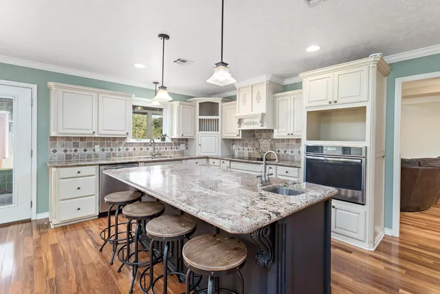 a kitchen with kitchen island granite countertop a sink a center island and stainless steel appliances
