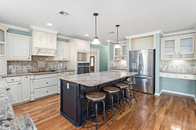 a kitchen with stainless steel appliances granite countertop a kitchen island hardwood floor and a sink