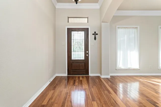 an empty room with wooden floor closet and windows