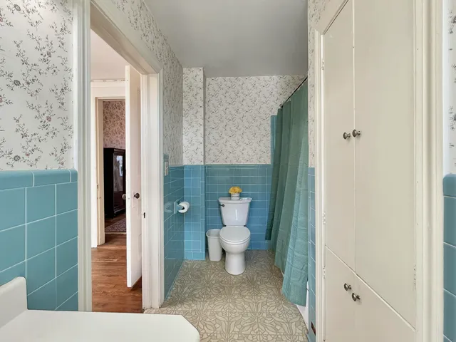 a view of a white house with a large tree