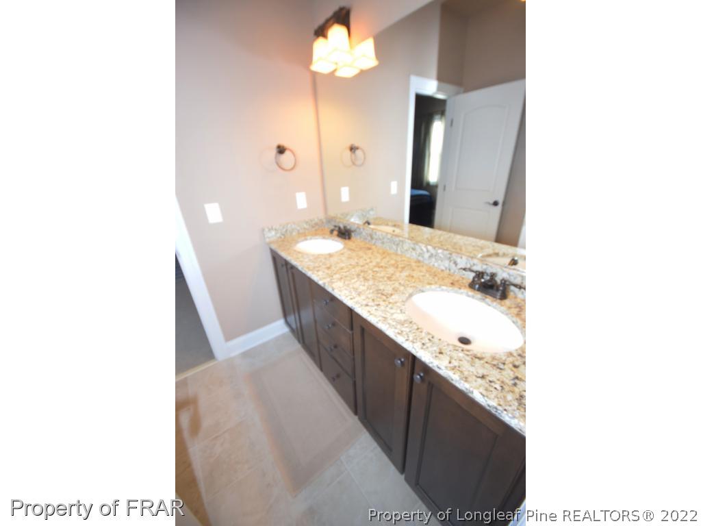 1804 Micahs Way North Spring Lake, NC 28390 - Photo 18 of 30 a bathroom with a granite countertop sink a mirror and a bathtub