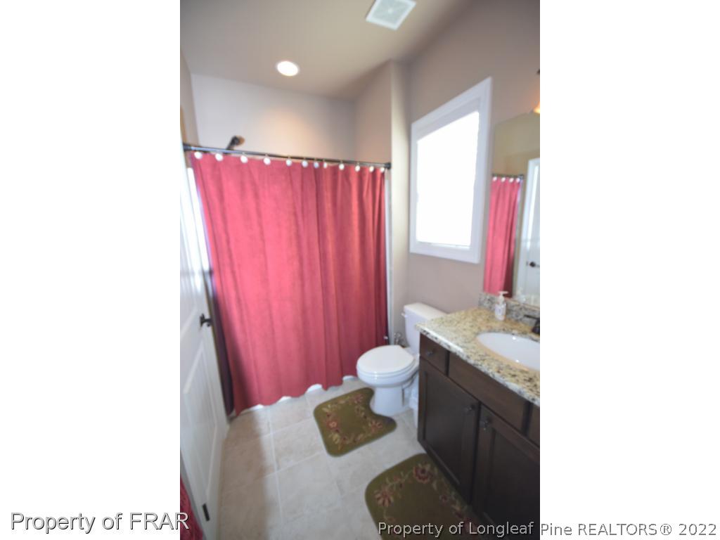 1804 Micahs Way North Spring Lake, NC 28390 - Photo 21 of 30 a bathroom with a granite countertop sink a mirror and a shower