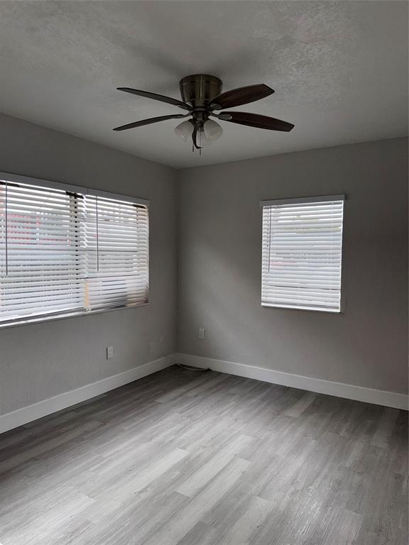 731 Northwest 56th Street, Unit 101 Miami, FL 33127 - Photo 8 of 11 an empty room with wooden floor and windows