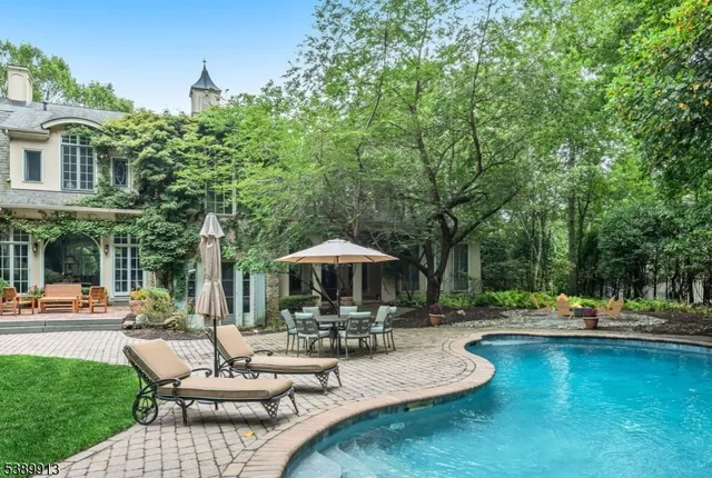 a view of swimming pool with outdoor seating and trees in the background