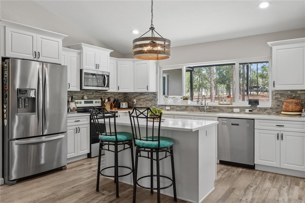 12929 Southwest 89th Street Dunnellon, FL 34432 - Photo 16 of 76 a kitchen with stainless steel appliances granite countertop a stove a sink dishwasher a refrigerator and a microwave oven with wooden floor