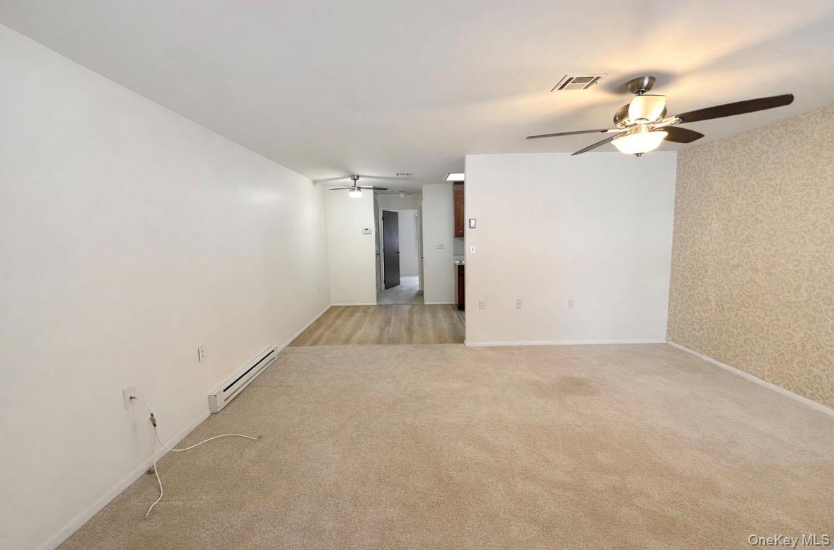 306 Torquay Court, Unit E Ridge, NY 11961 - Photo 4 of 12 an empty room with a chandelier fan and windows