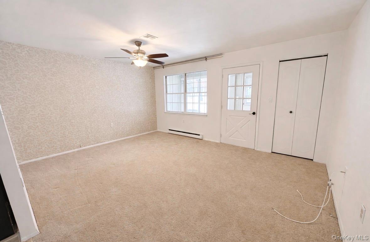 306 Torquay Court, Unit E Ridge, NY 11961 - Photo 5 of 12 wooden floor in an empty room with a window