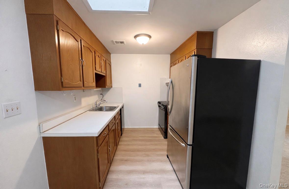306 Torquay Court, Unit E Ridge, NY 11961 - Photo 10 of 12 a kitchen with stainless steel appliances granite countertop a refrigerator and a sink