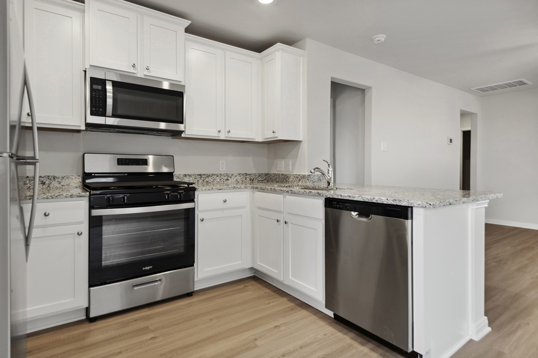 15866 Berry Hl Drive Conroe, TX 77303 - Photo 13 of 20 a kitchen with granite countertop white cabinets stainless steel appliances and wooden floor