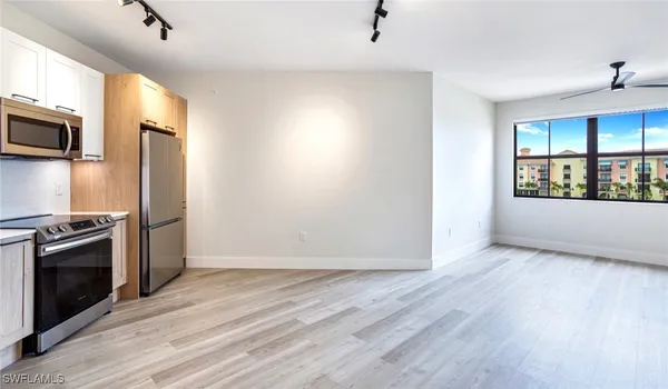 a view of a kitchen with wooden floor electronic appliances and windows
