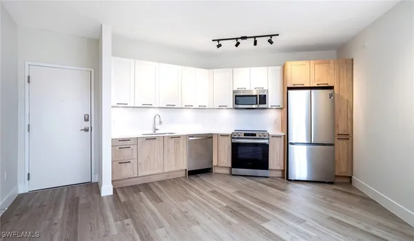 a kitchen with a refrigerator stove and wooden floors