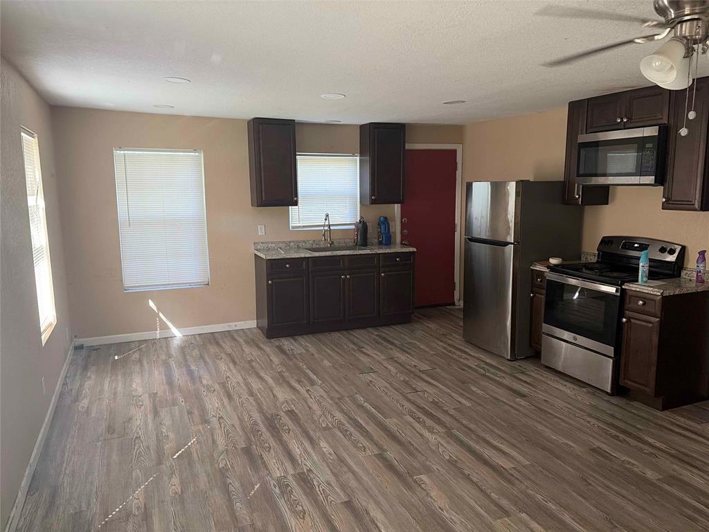 701 West Colorado Street Groesbeck, TX 76642 - Photo 4 of 12 Kitchen featuring stainless steel appliances, dark wood finish cabinets, dark wood-style floors, and a ceiling fan