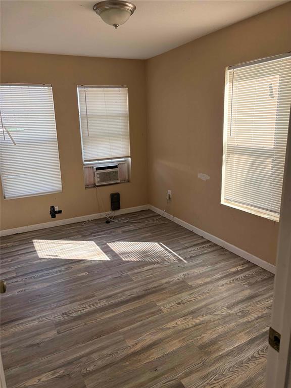 701 West Colorado Street Groesbeck, TX 76642 - Photo 6 of 12 Empty room featuring dark wood-style floors, healthy amount of natural light, and cooling unit