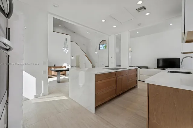 a room with stainless steel appliances kitchen island granite countertop a stove and a sink