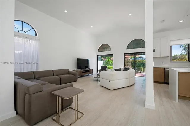 a living room with stainless steel appliances furniture a rug and a view of kitchen