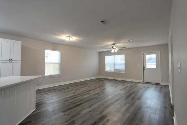 an empty room with wooden floor and windows