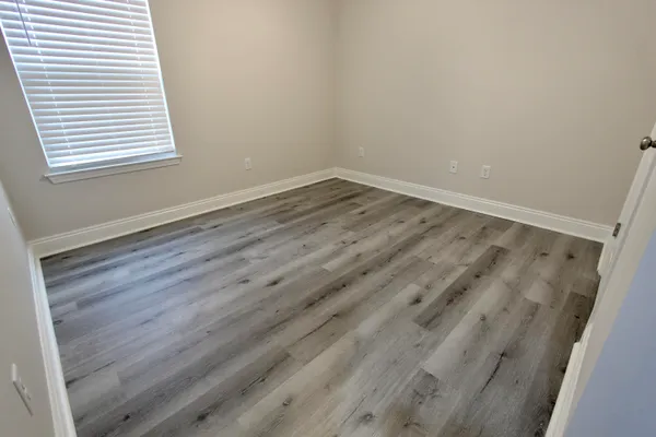 a view of a room that has wooden floor and a window