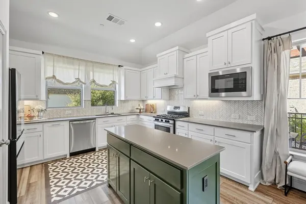 a kitchen with stainless steel appliances a white cabinets and a window