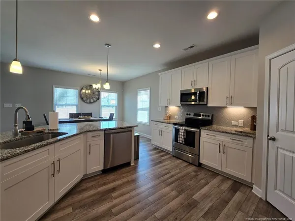 a kitchen with kitchen island granite countertop a sink cabinets and stainless steel appliances