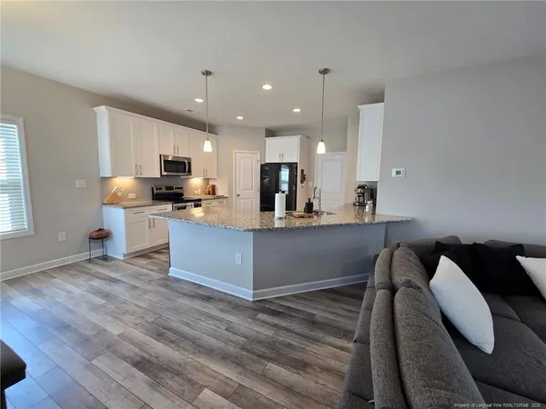 a kitchen with kitchen island granite countertop wooden floors and wide window