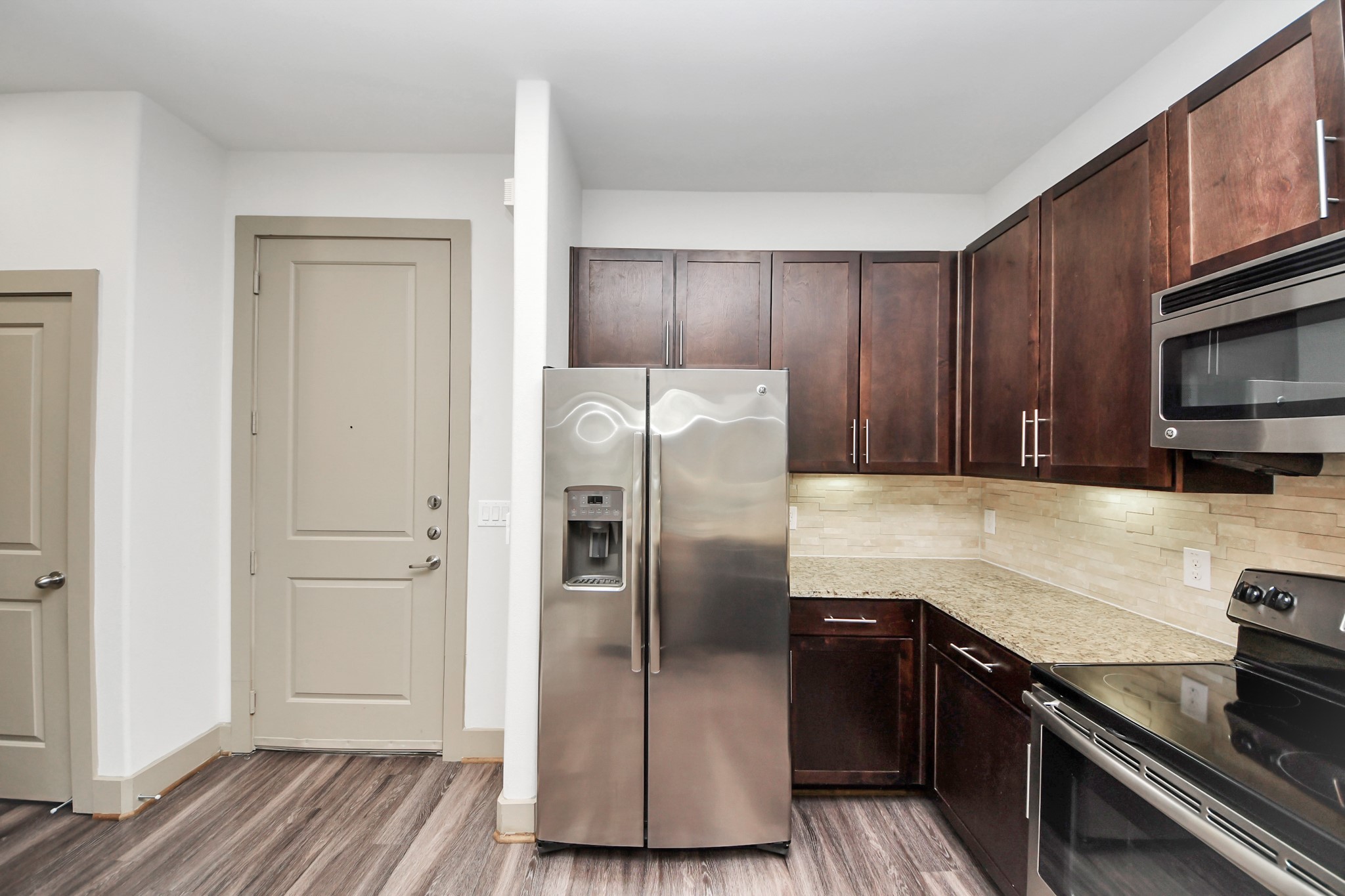 3800 Main Street, Unit 1 226 Houston, TX 77002 - Photo 24 of 50 a kitchen with granite countertop a refrigerator stove and wooden cabinets