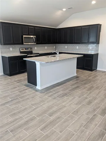 a kitchen with stainless steel appliances granite countertop a stove a sink and a microwave