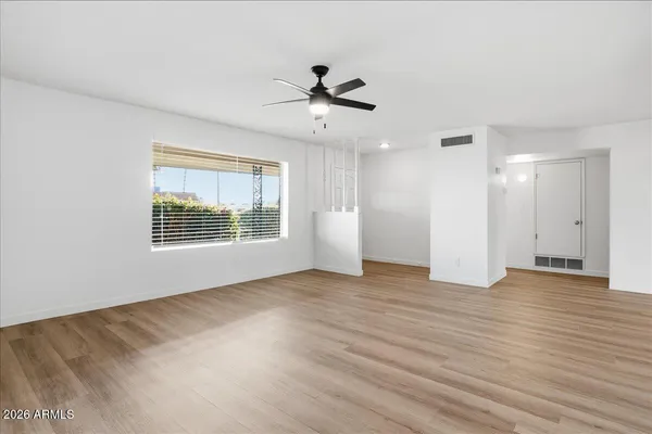 a view of an empty room with a window and wooden floor