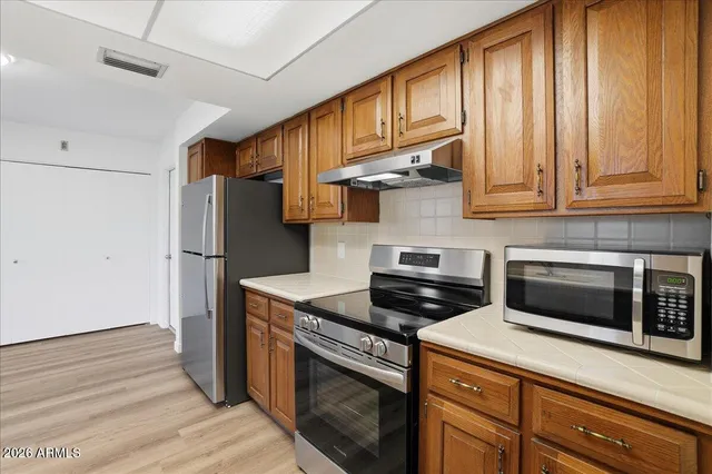 a kitchen with stainless steel appliances granite countertop a stove a refrigerator and a microwave