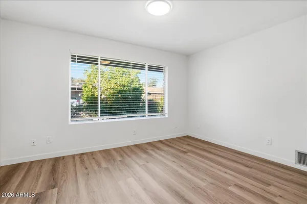 a view of an empty room with wooden floor and a window