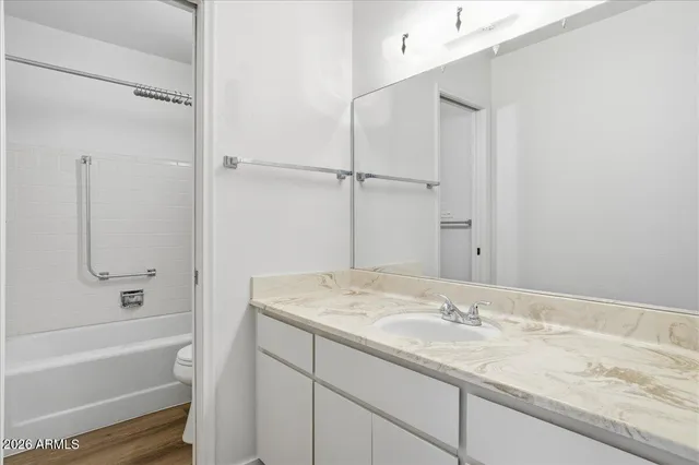 a bathroom with a granite countertop sink mirror and a bath tub