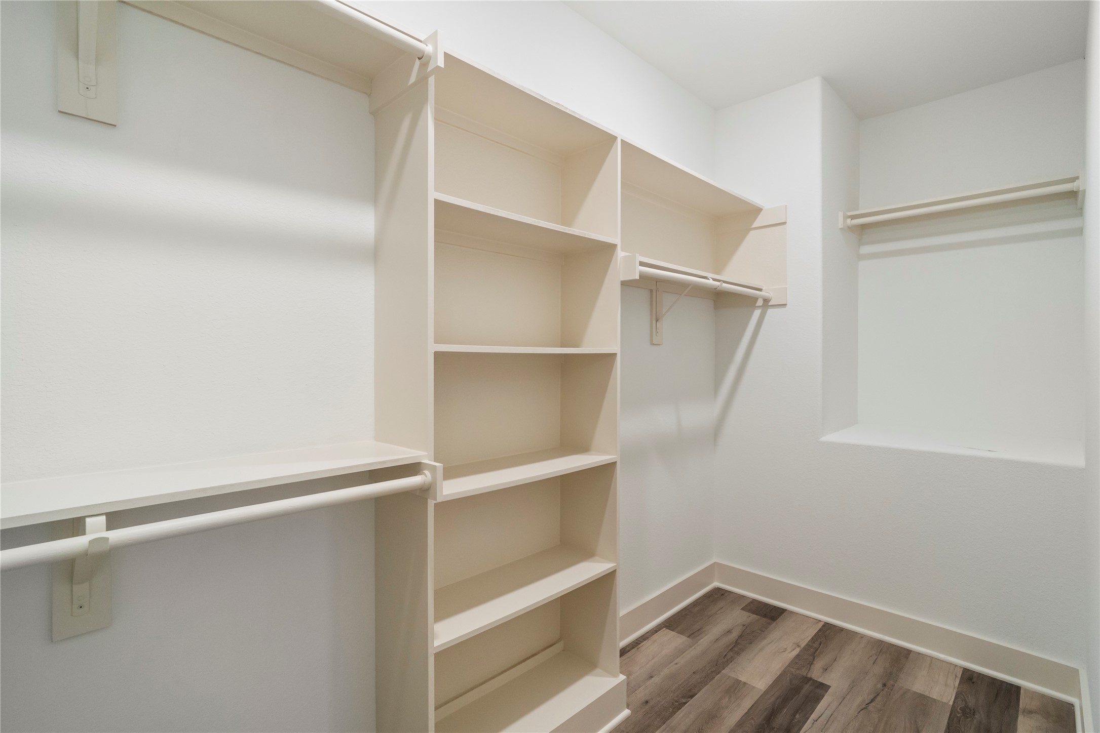 5629 Malmedy Road Houston, TX 77033 - Photo 15 of 24 Spacious walk-in closet featuring ample shelving and hanging space, complemented by stylish wood flooring.