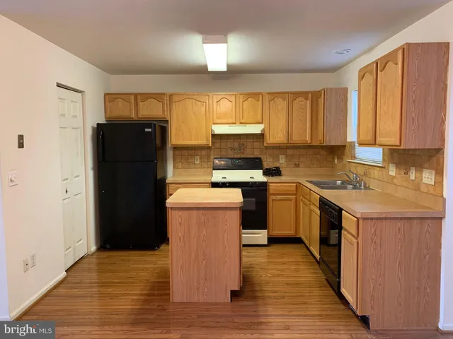 a kitchen with a refrigerator a stove a sink dishwasher and a refrigerator with wooden floor