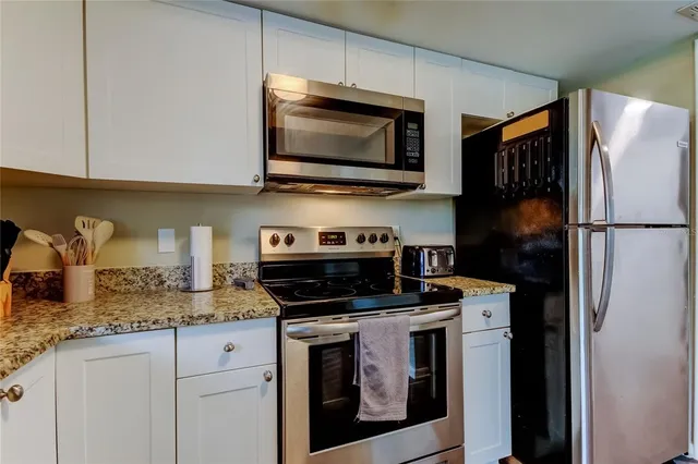 a kitchen with stainless steel appliances granite countertop a stove microwave and refrigerator
